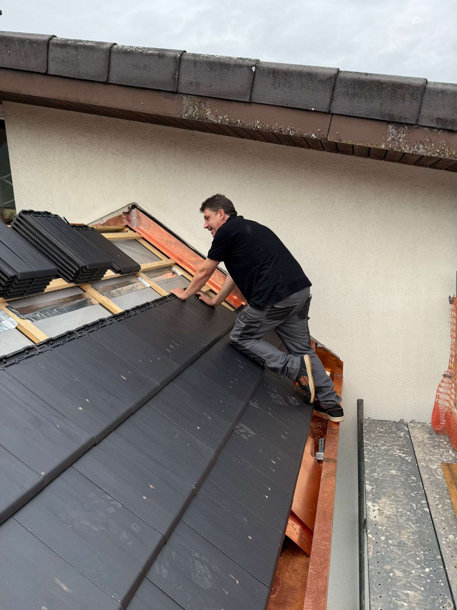 Dachdecker montiert neue Flachziegel auf VerdanaTherm-Aufsparrendämmung mit Kupfer-Anschlussblechen